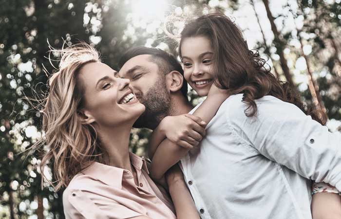 Family of three smiling outside